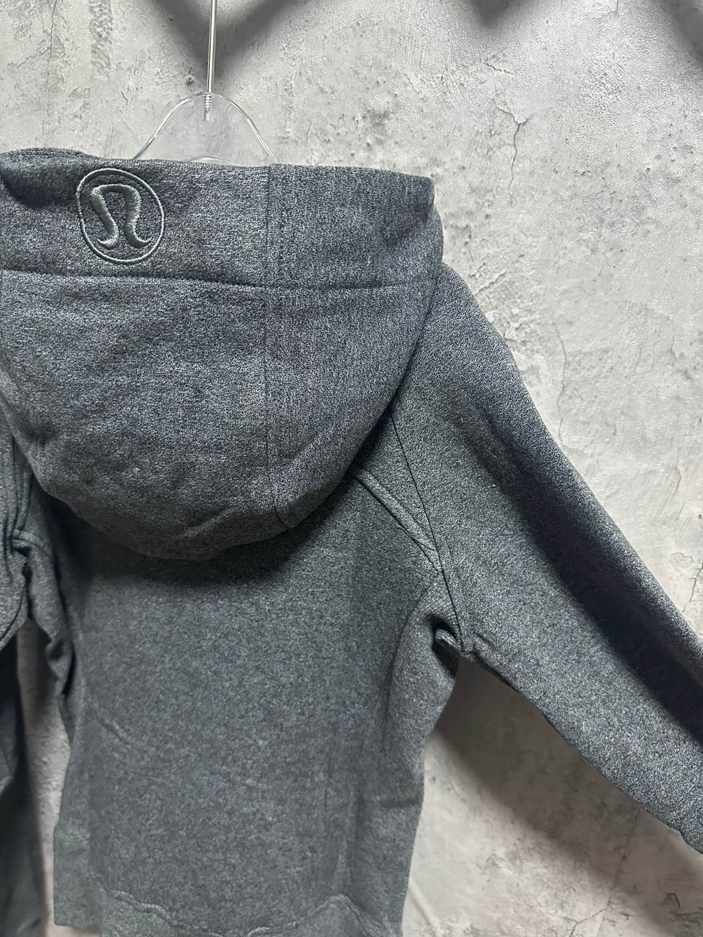 Dark gray zip-up hoodie back with raised hood, seams, and ribbed cuffs