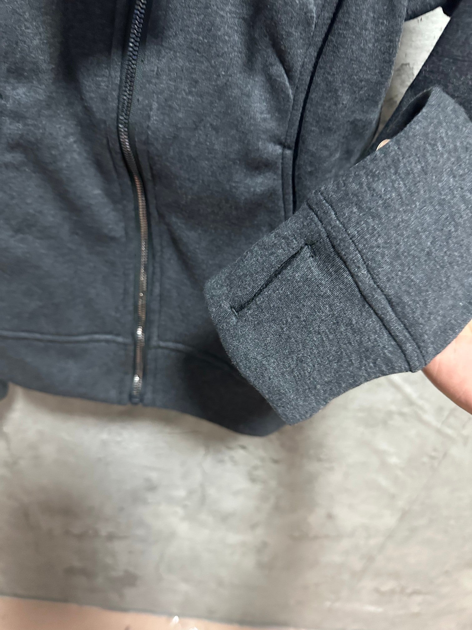 Dark gray zip-up hoodie lower front close-up with zipper and seam details
