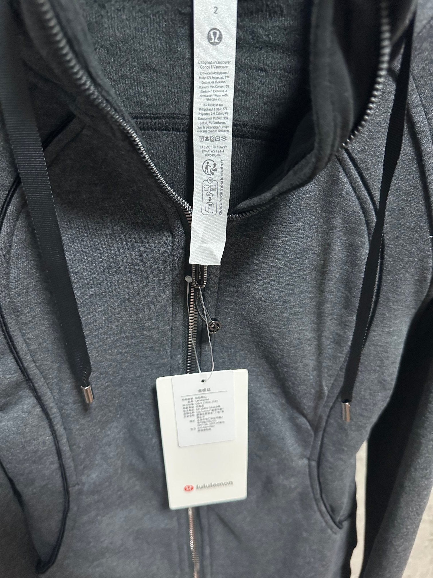 Dark gray zip-up hoodie collar area with inner hood and hanging brand tags