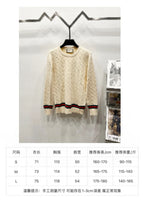 Cream cable-knit sweater with multicolor striped hem; size chart shown below