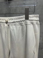 Cream sweatpants with elastic waistband and drawstring cord, front view
