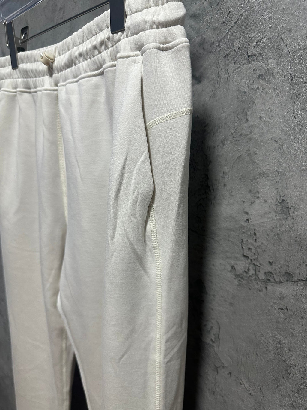 Cream sweatpants side view with elastic waist and tapered straight leg