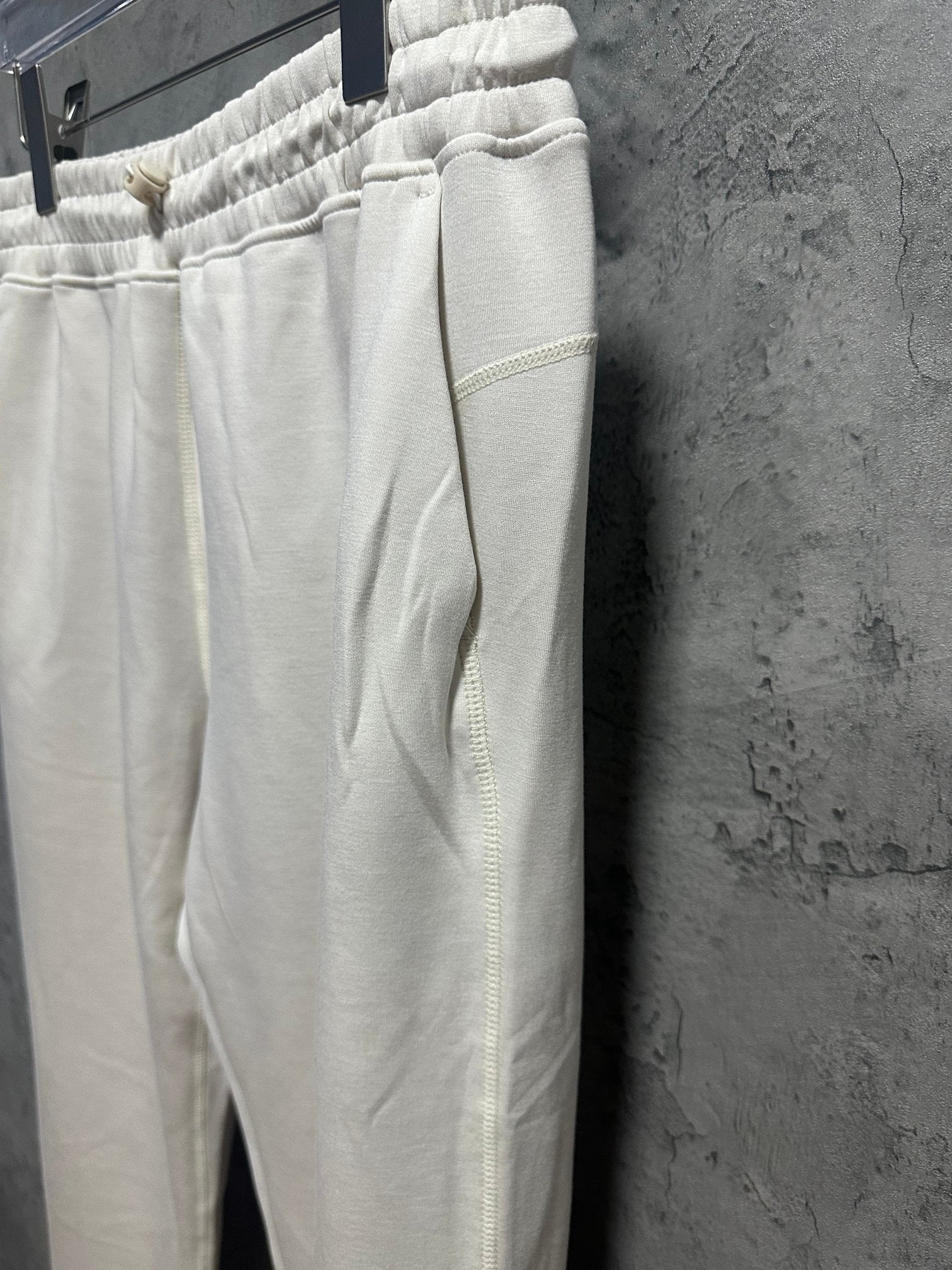 Cream sweatpants side view with elastic waist and tapered straight leg