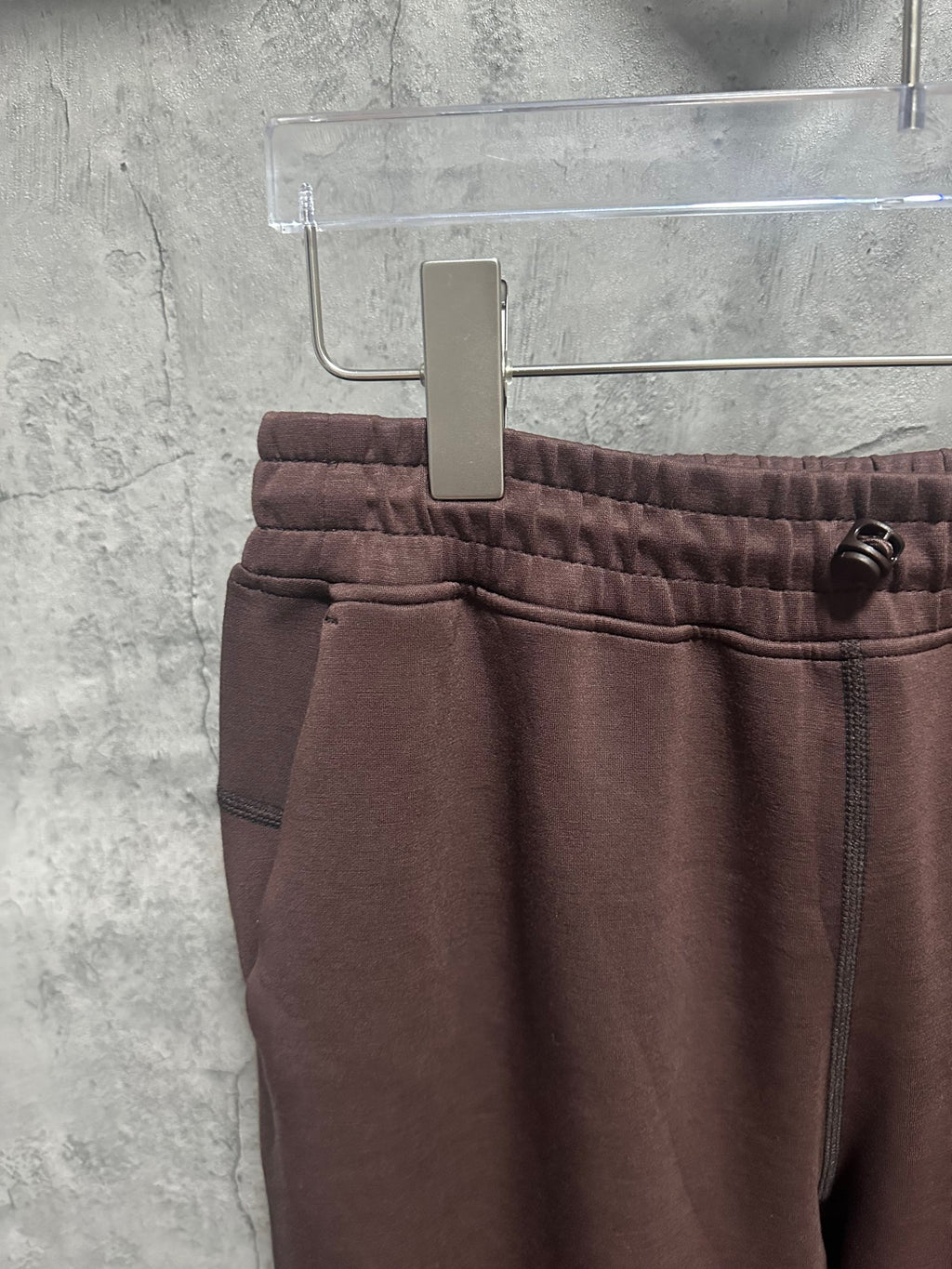 Maroon sweatpants with elastic waistband, front seam, and small pocket detail