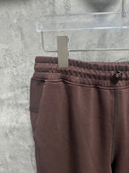 Maroon sweatpants with elastic waistband, front seam, and small pocket detail