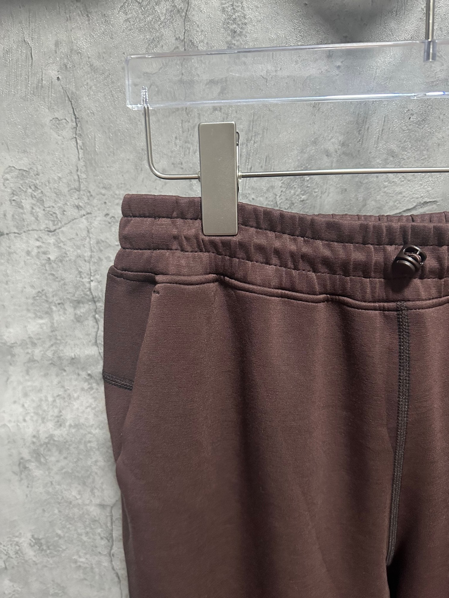 Maroon sweatpants with elastic waistband, front seam, and small pocket detail