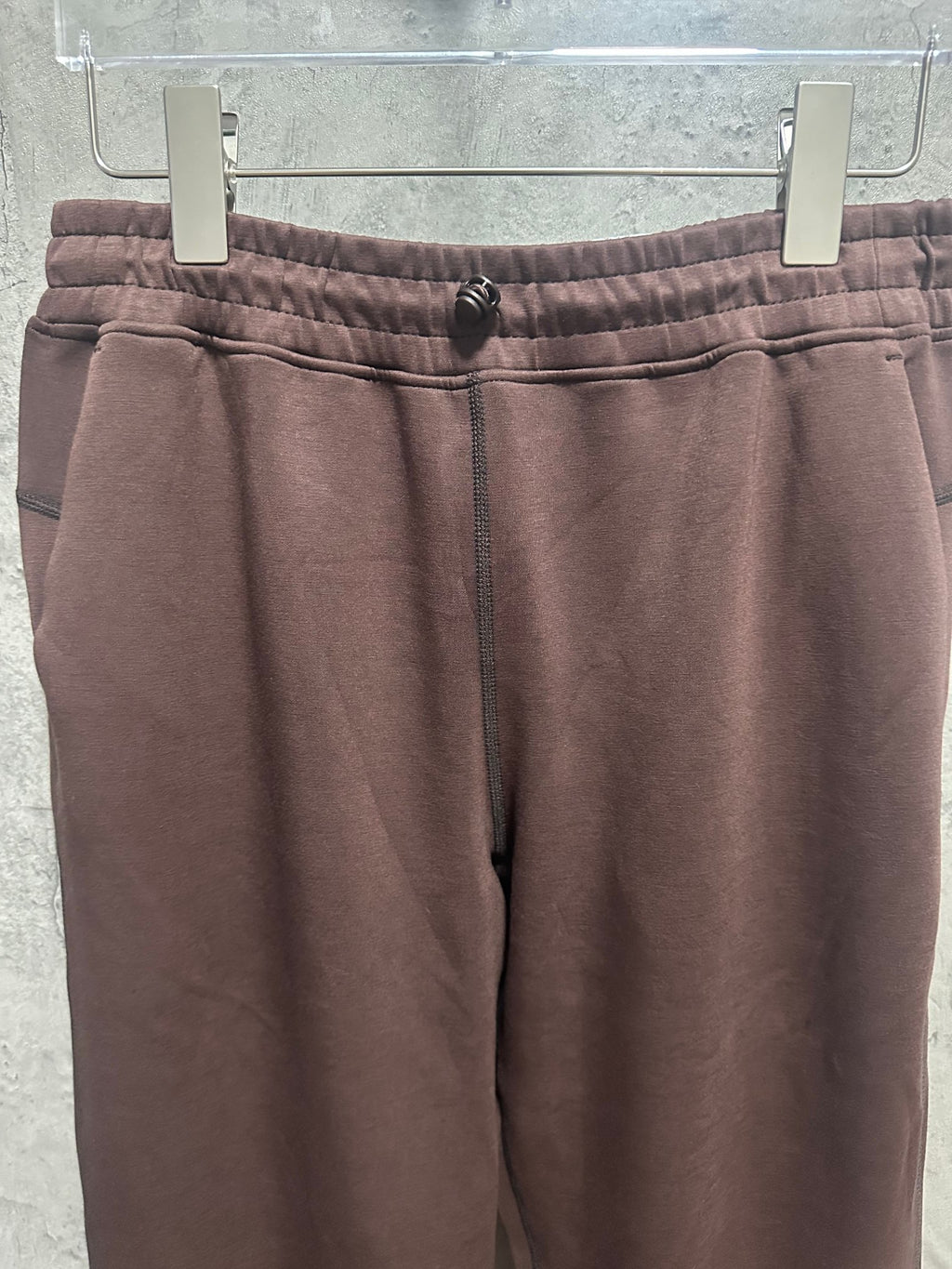 Close-up of dark brown pants waistband with elastic and drawstring ties