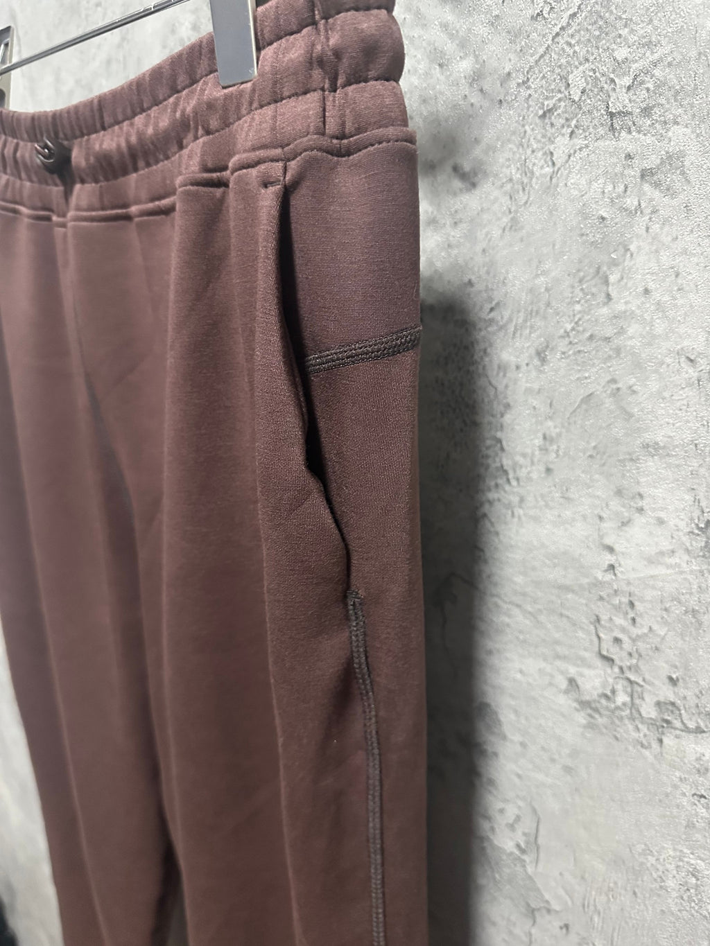 Maroon sweatpants side view with tapered ankle hem and visible pocket seam