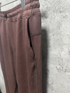Maroon sweatpants side view with tapered ankle hem and visible pocket seam