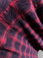 Long-sleeve plaid shirt fabric close-up, red grid pattern on dark base