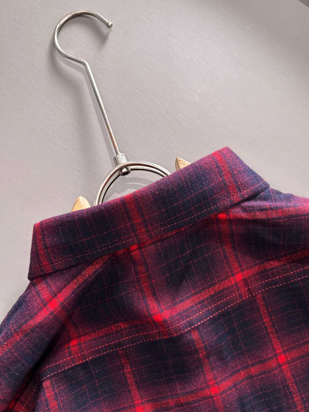 Long-sleeve plaid shirt on hanger, red and dark blue check pattern at shoulders