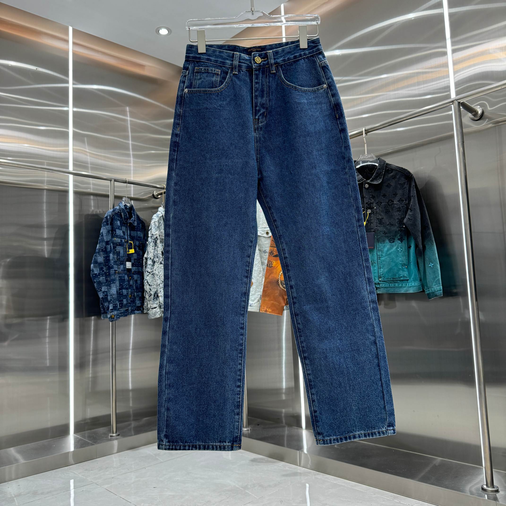 Blue denim Louis Vuitton pants on hanger, straight-leg fit with belt loops