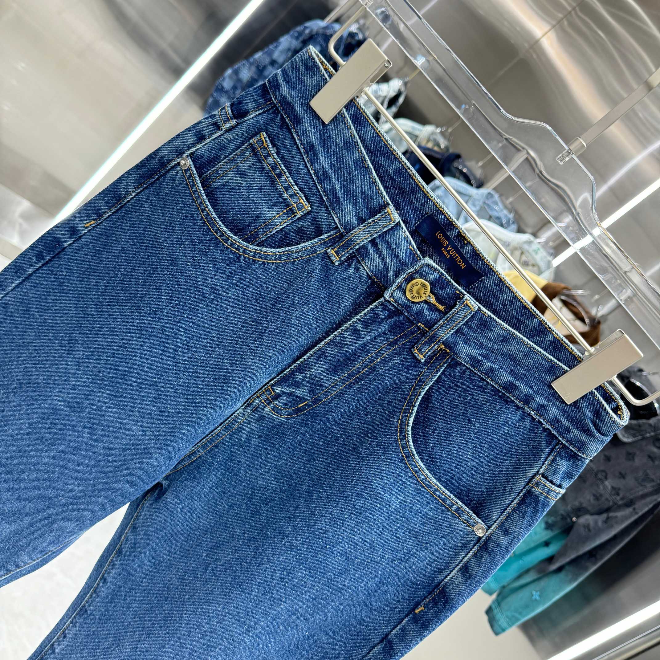 Blue denim Louis Vuitton pants close-up, back patch pockets with gold button