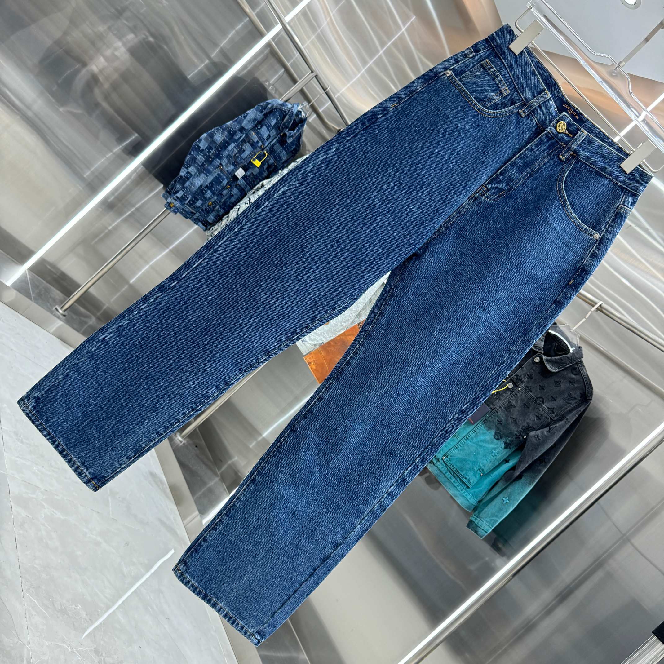 Blue denim Louis Vuitton pants laid out, long straight legs with stitched hems