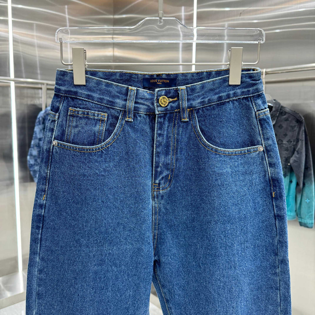 Blue denim Louis Vuitton pants waistband close-up, gold logo button and belt loops