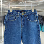 Blue denim Louis Vuitton pants waistband close-up, gold logo button and belt loops
