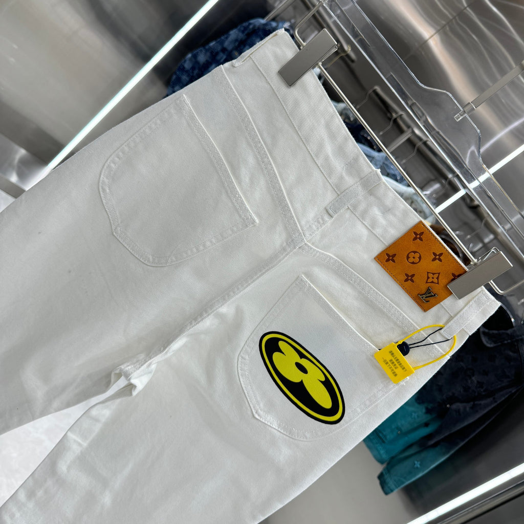 White denim pants with round yellow-and-black logo patch and small side label