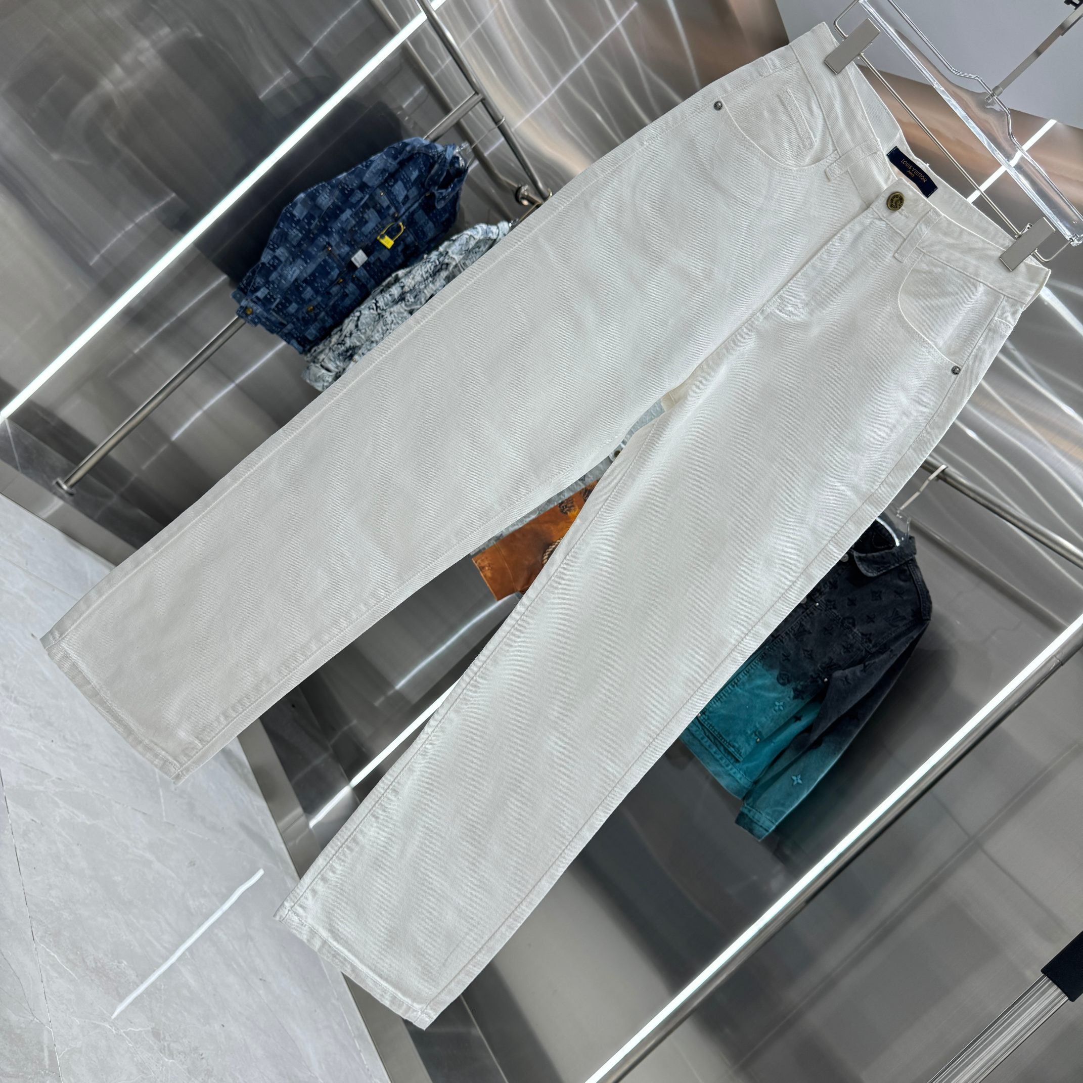 White denim pants laid out, showing front pockets and belt loops