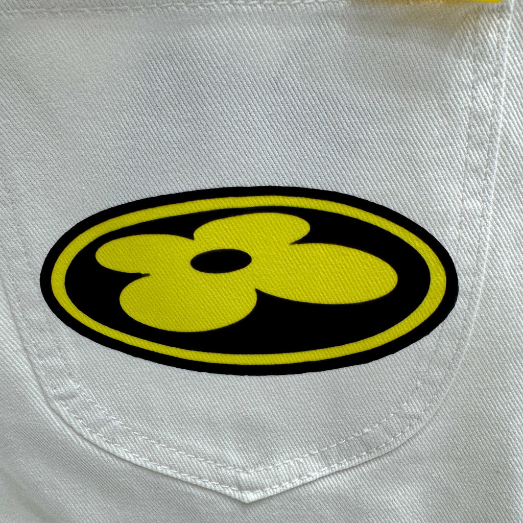 White denim pocket with yellow-and-black round logo patch