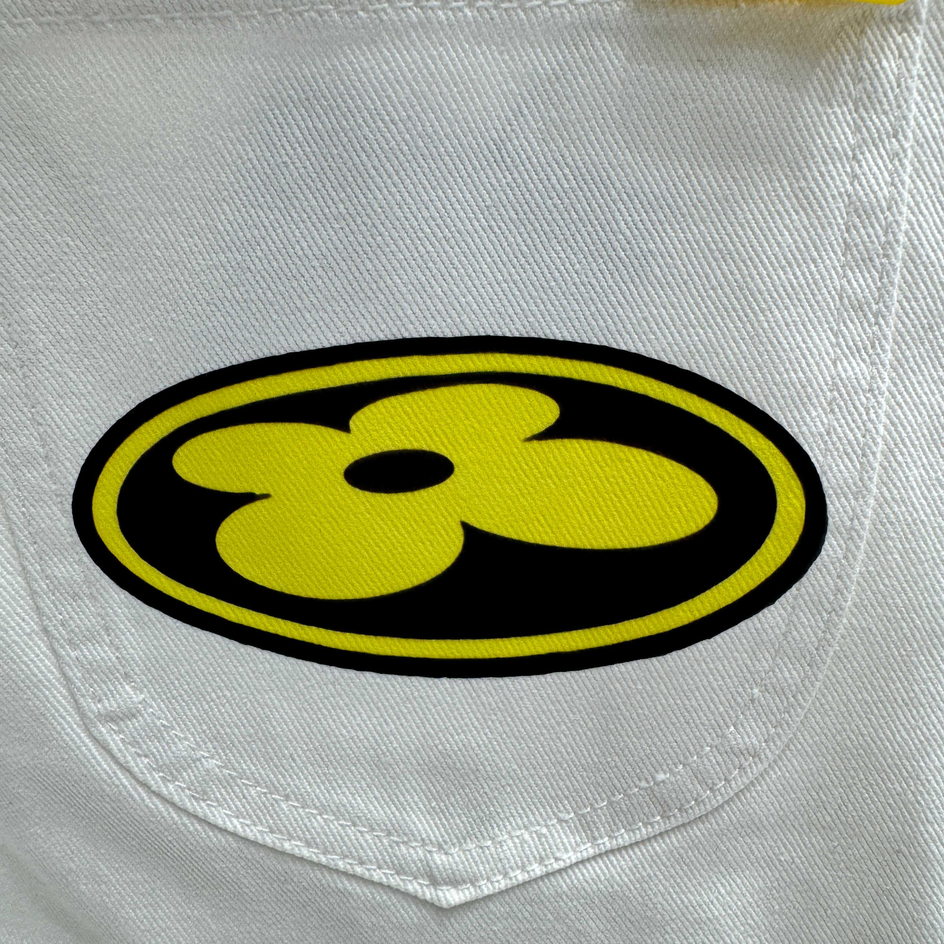 White denim pocket with yellow-and-black round logo patch