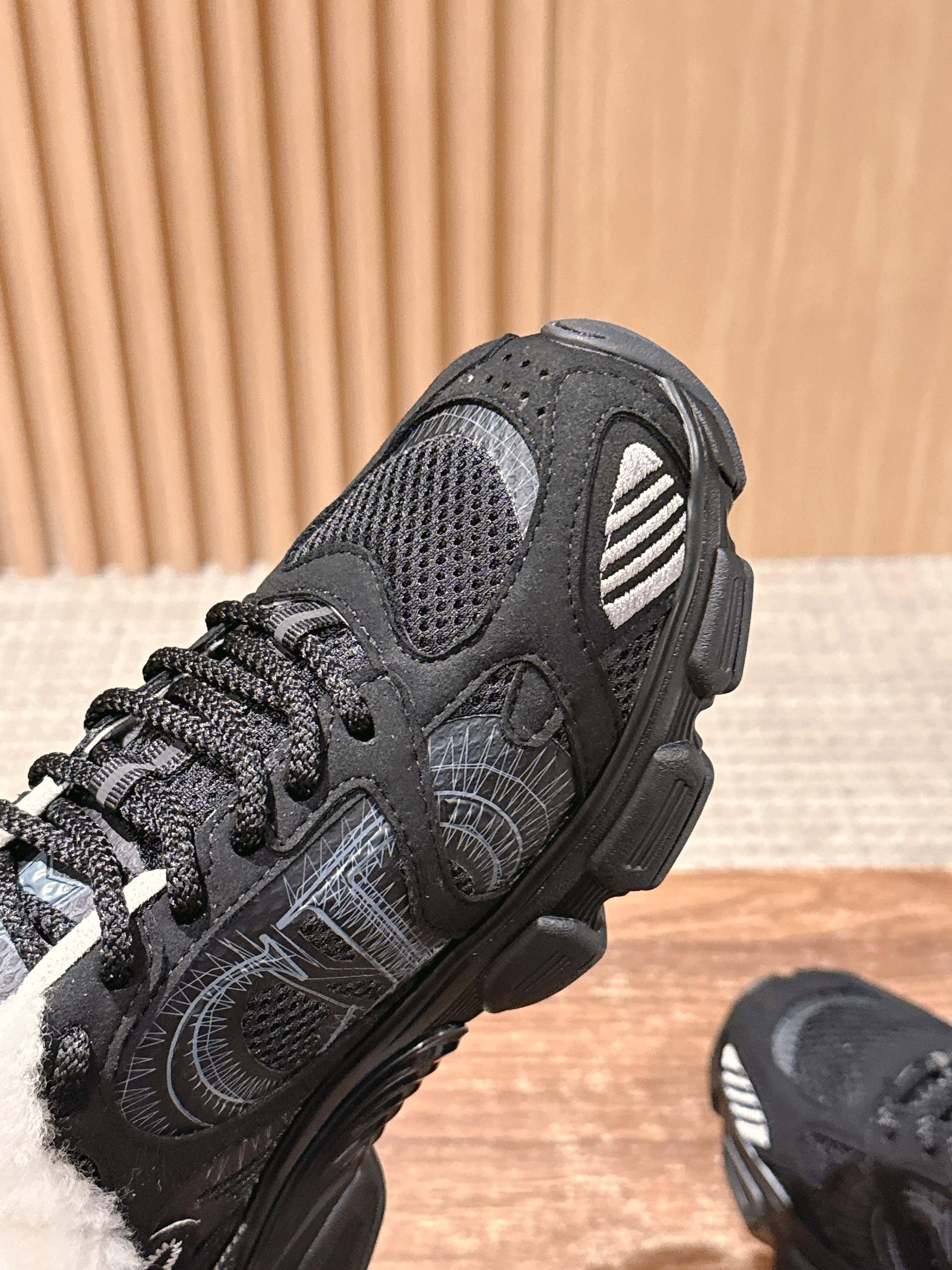 Black unisex sneaker upper close-up with mesh panels and lace fastening