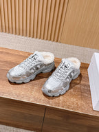 Silver metallic sneakers with faux-fur cuffs, lace-up front detail, on wooden surface