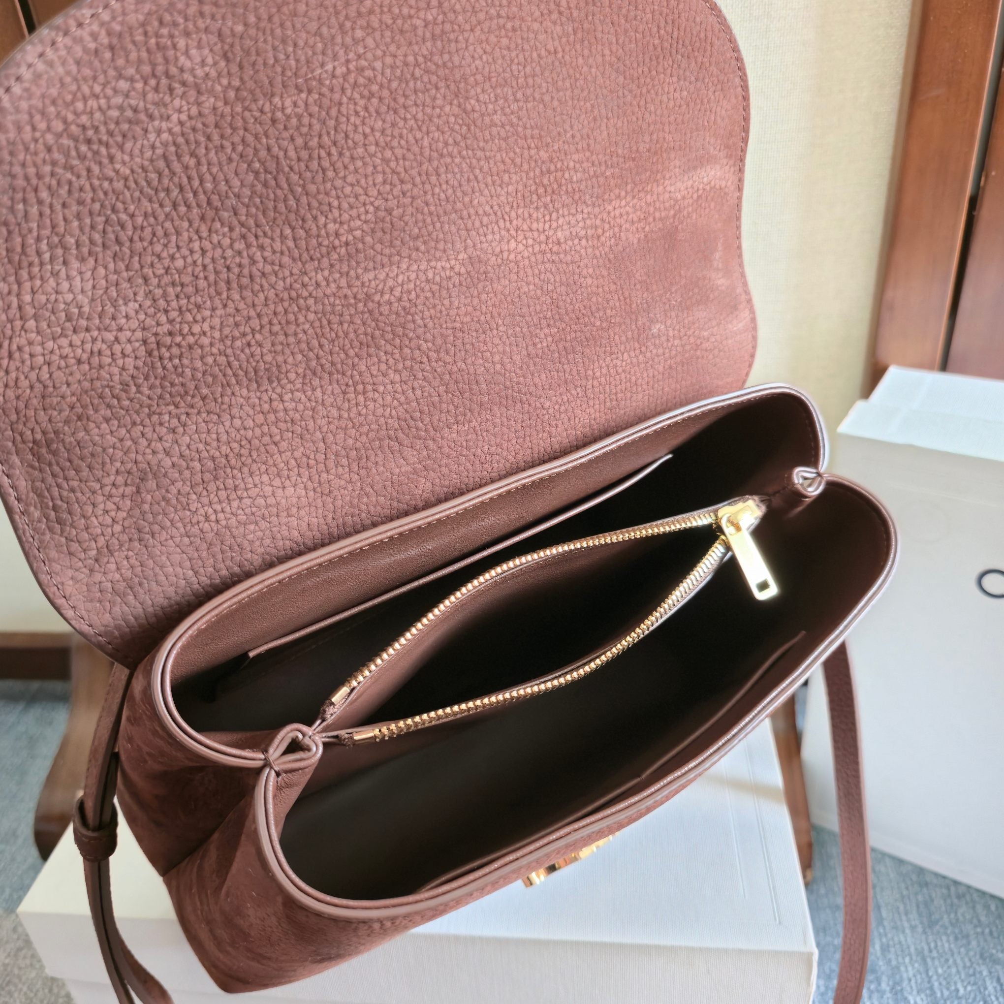 Celine handbag open top with dark interior, gold zipper, and brown leather strap at side