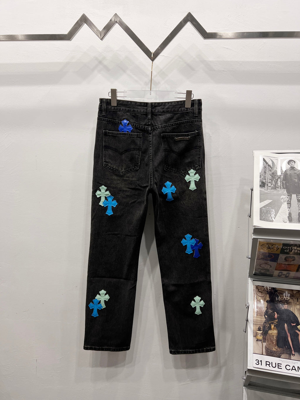 Black denim pants with blue and light-green patch designs, rear view