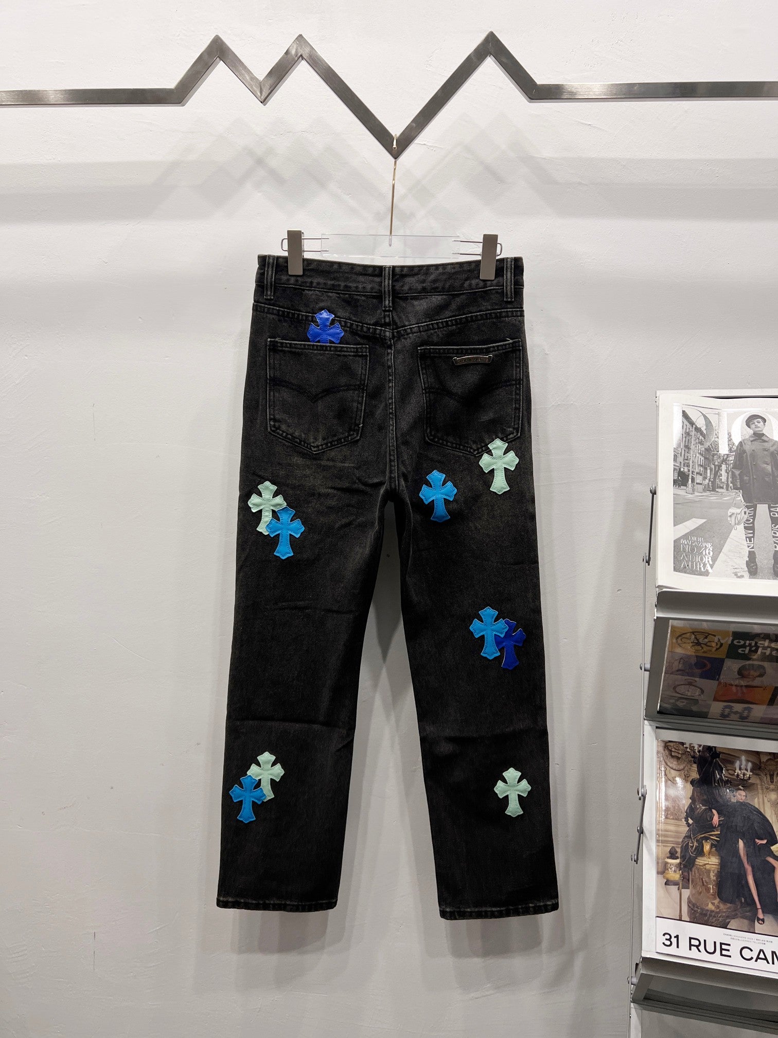 Black denim pants with blue and light-green patch designs, rear view