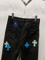 Black denim pants with cross-style patches on the lower back leg