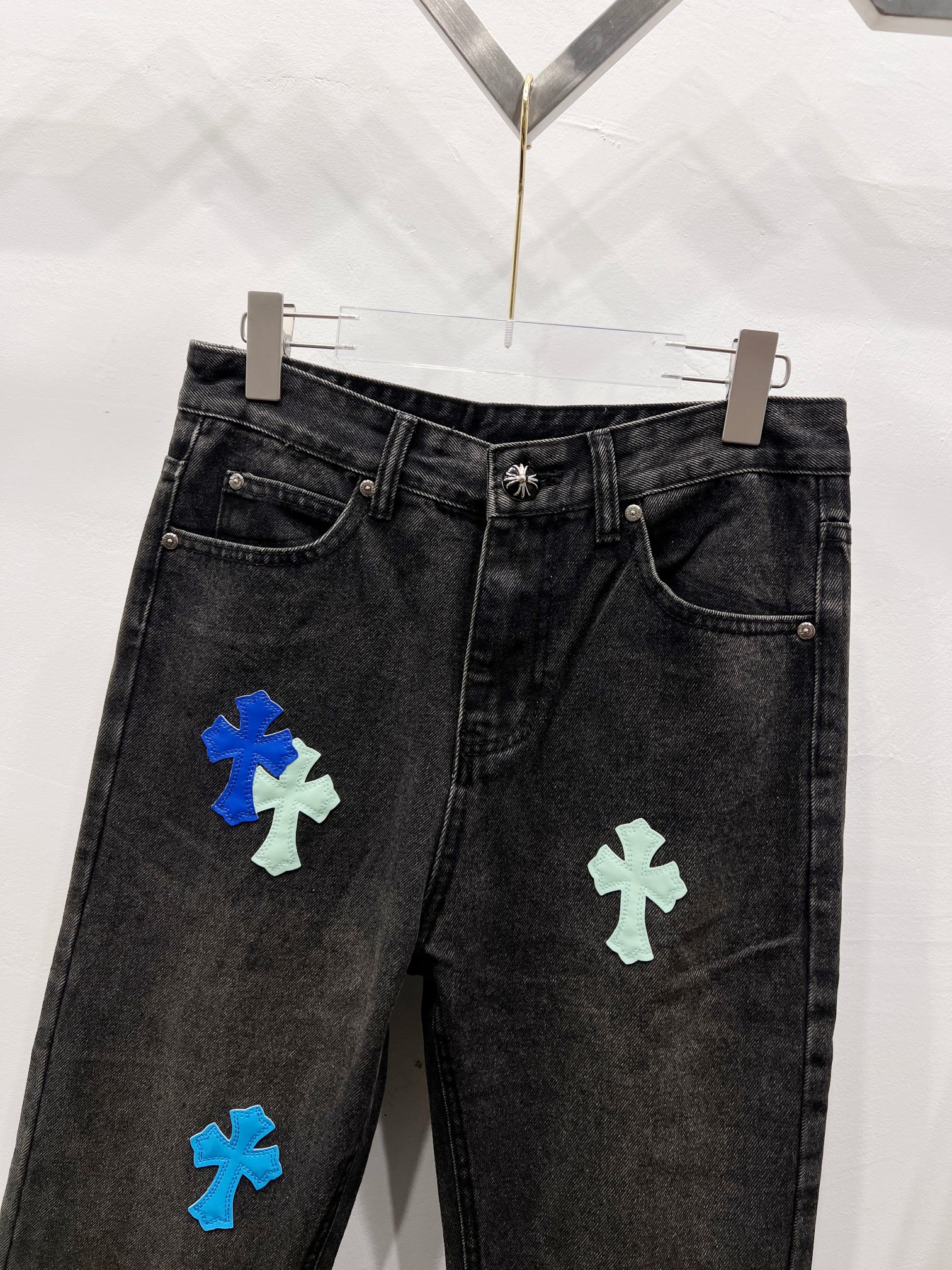 Black denim pants with colorful cross-style patches on the front legs