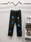 Black denim pants with blue and light-green patch designs, front view