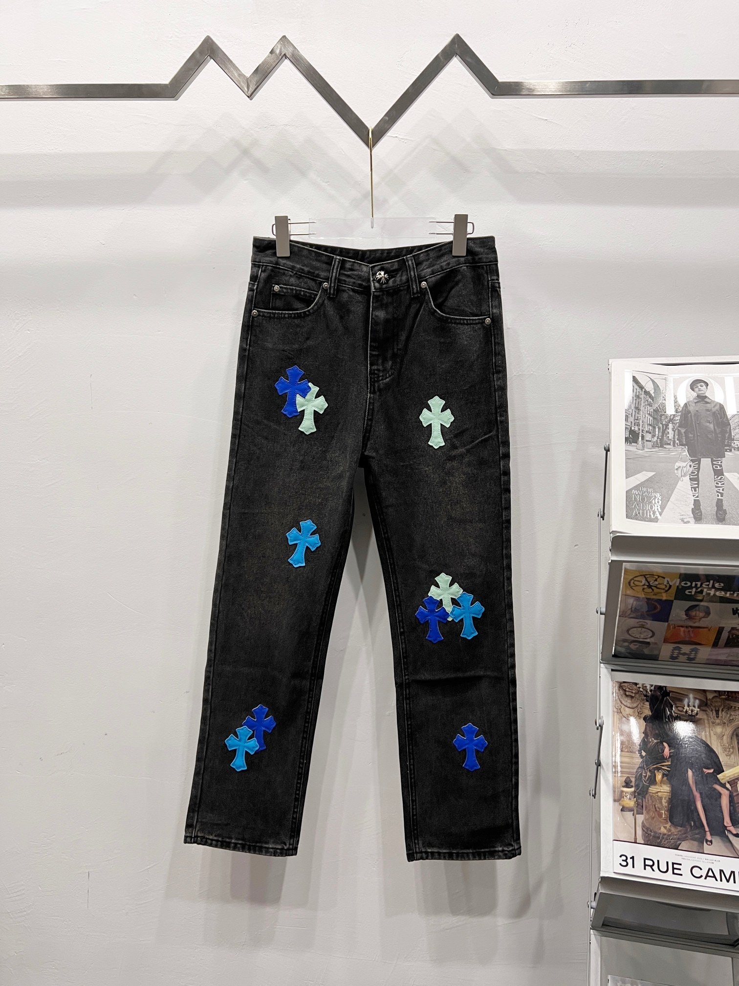 Black denim pants with blue and light-green patch designs, front view