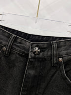 Black denim pants waistband with decorative stitched emblem on belt area