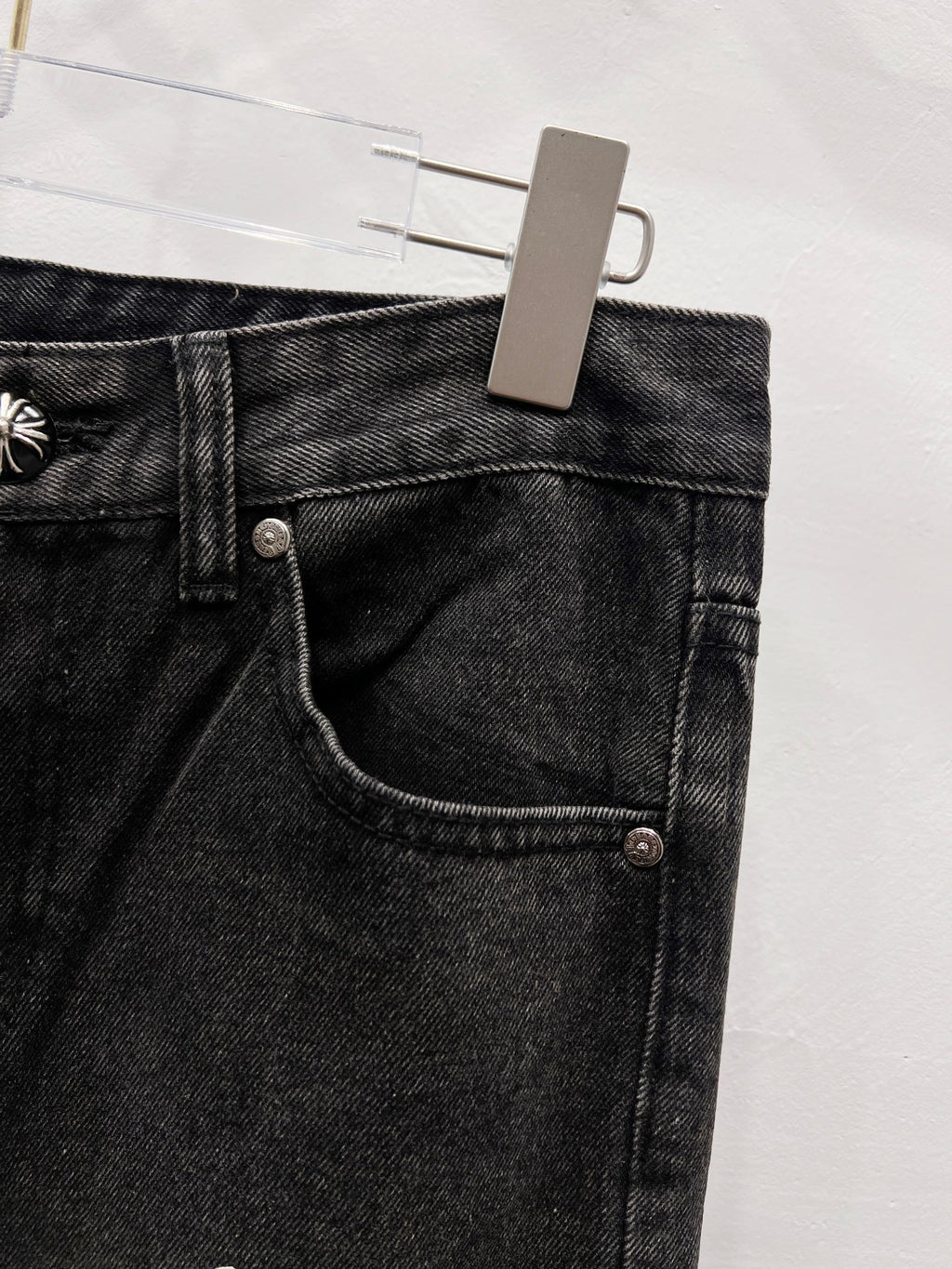 Black denim pants with front pocket seam and metal button detail