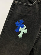Black denim pants with blue and light-green cross patches on leg