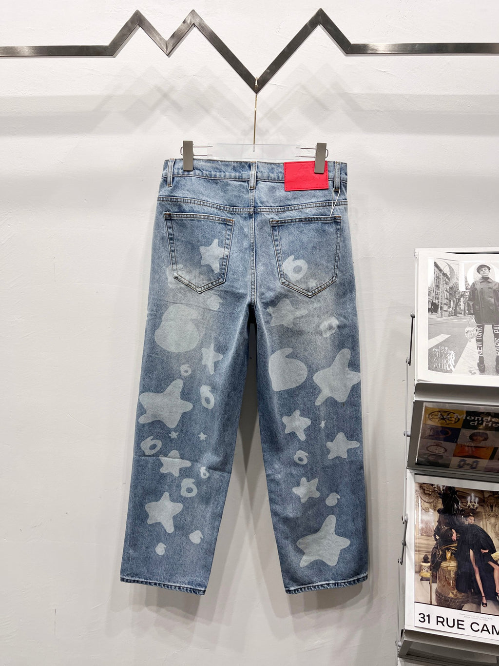 Light blue denim pants with star and heart print, red tag on waistband