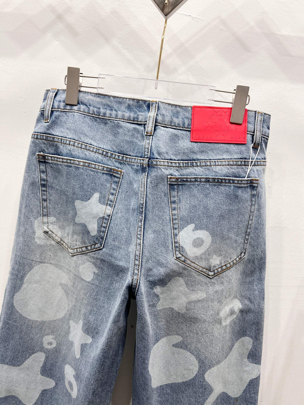 Light blue denim pants with star-and-heart print, back pockets and red logo label