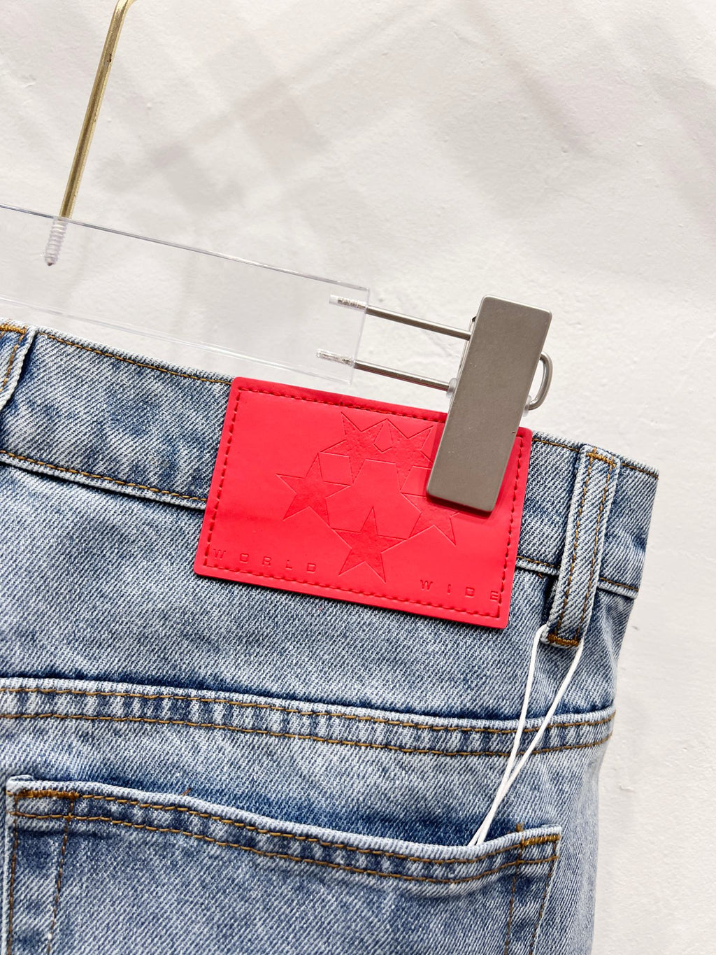 Red star-embossed patch detail on light blue denim pants pocket