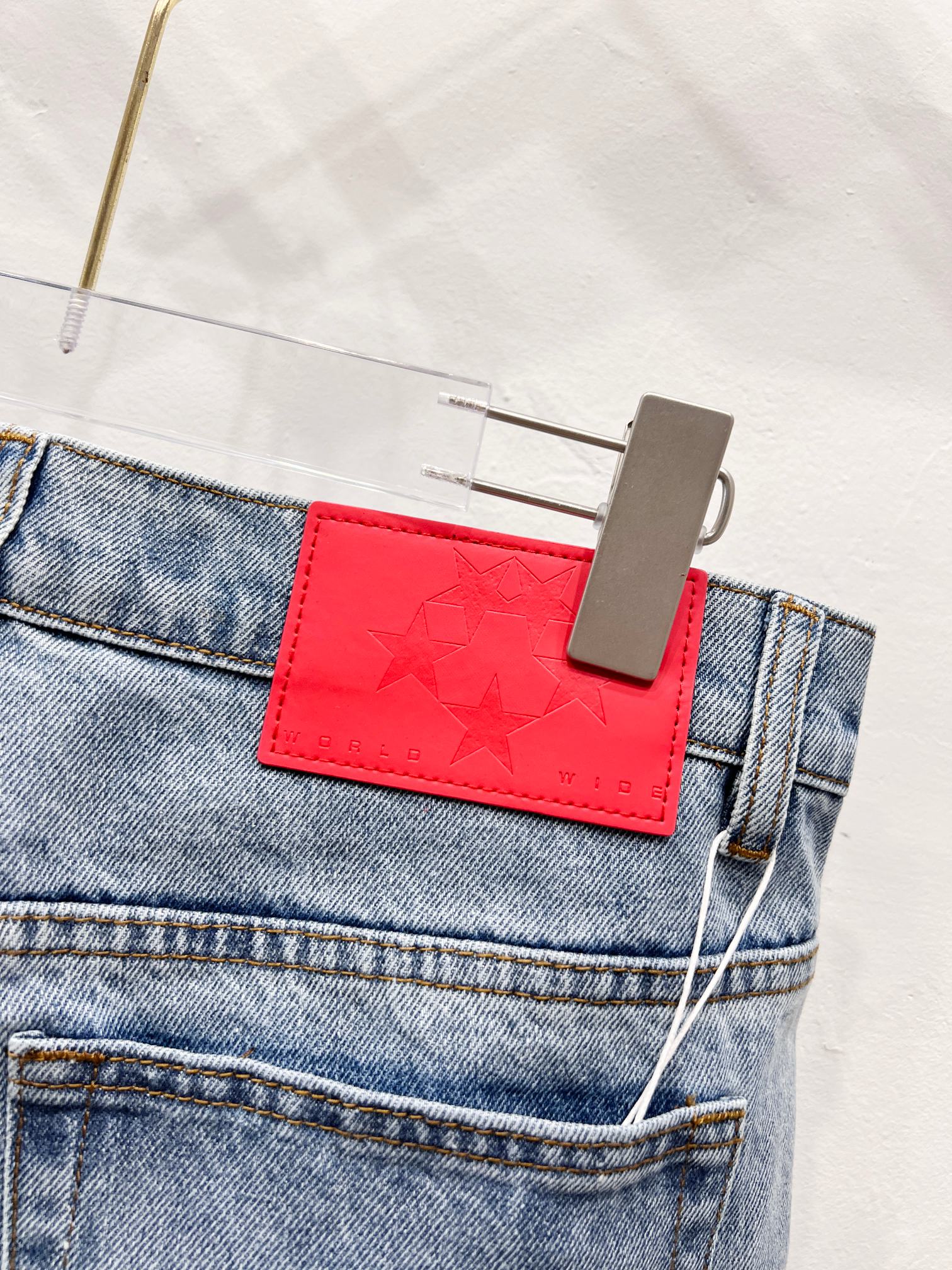 Red star-embossed patch detail on light blue denim pants pocket