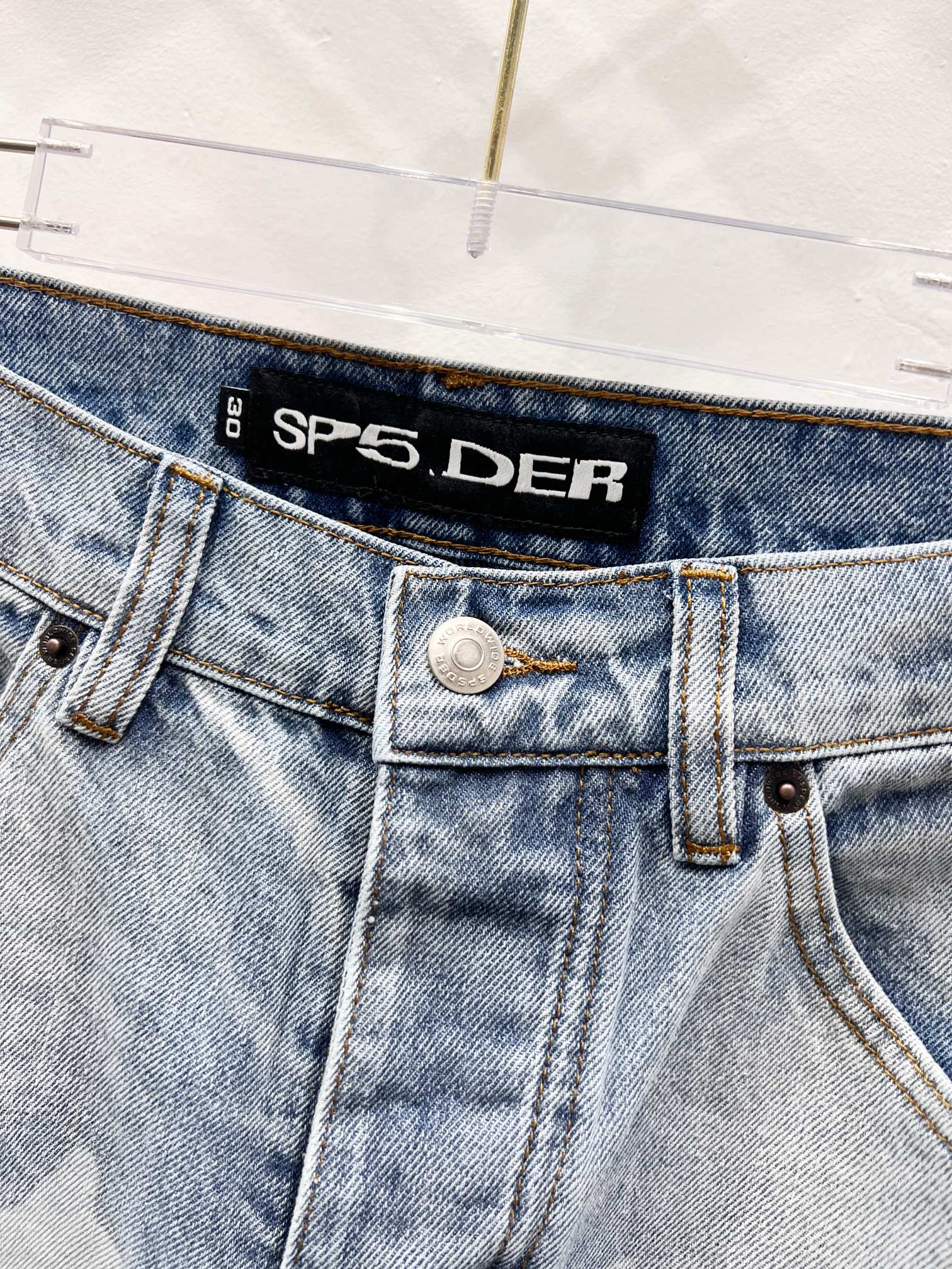 Light blue denim jeans with SP5DER logo waistband and buttoned fly