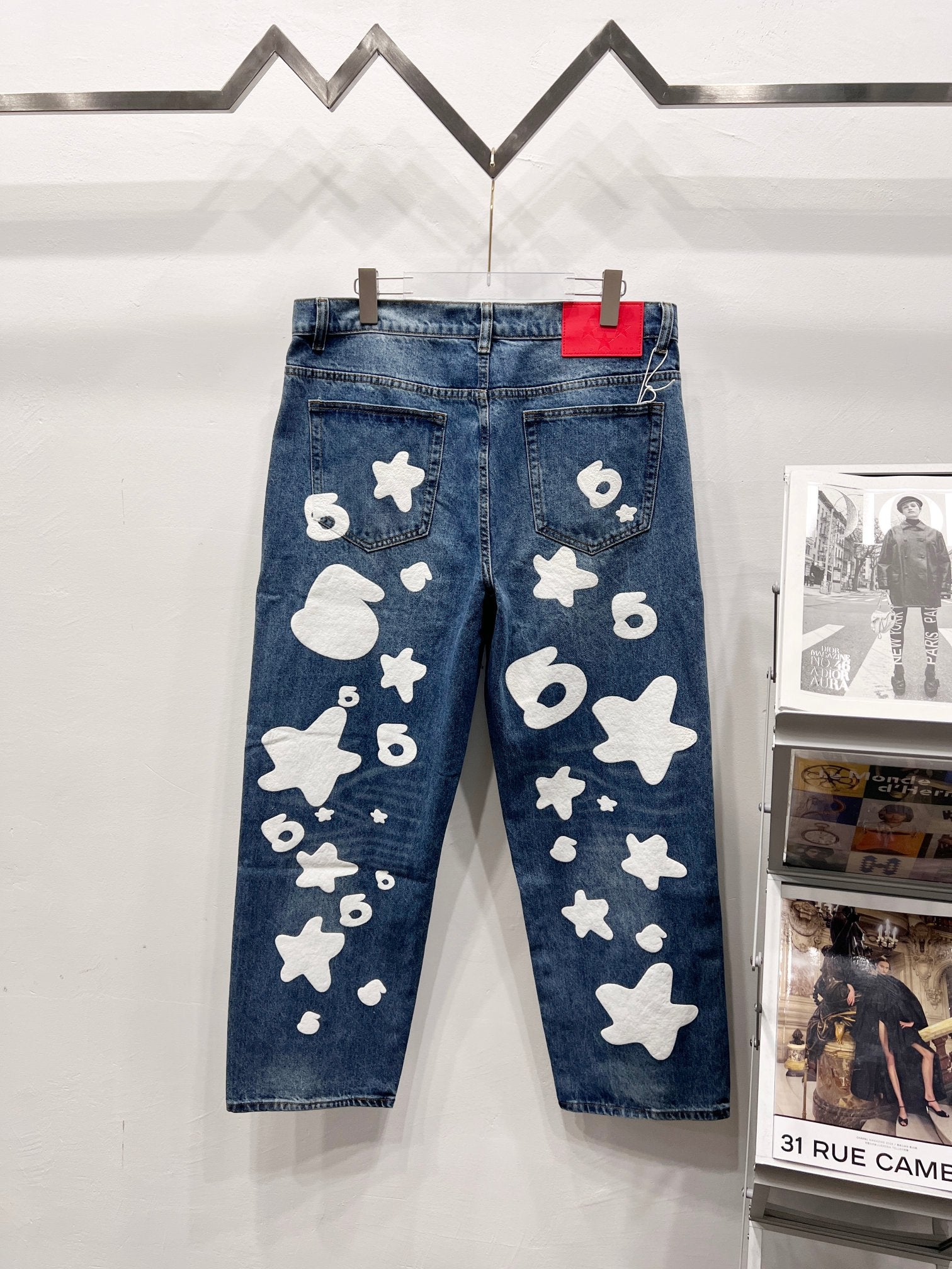Blue denim pants with white graphic patches, side front view