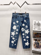 Blue denim pants with white graphic patches, front view on hangers