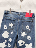 Blue denim pants with white graphic patches, close-up back pockets
