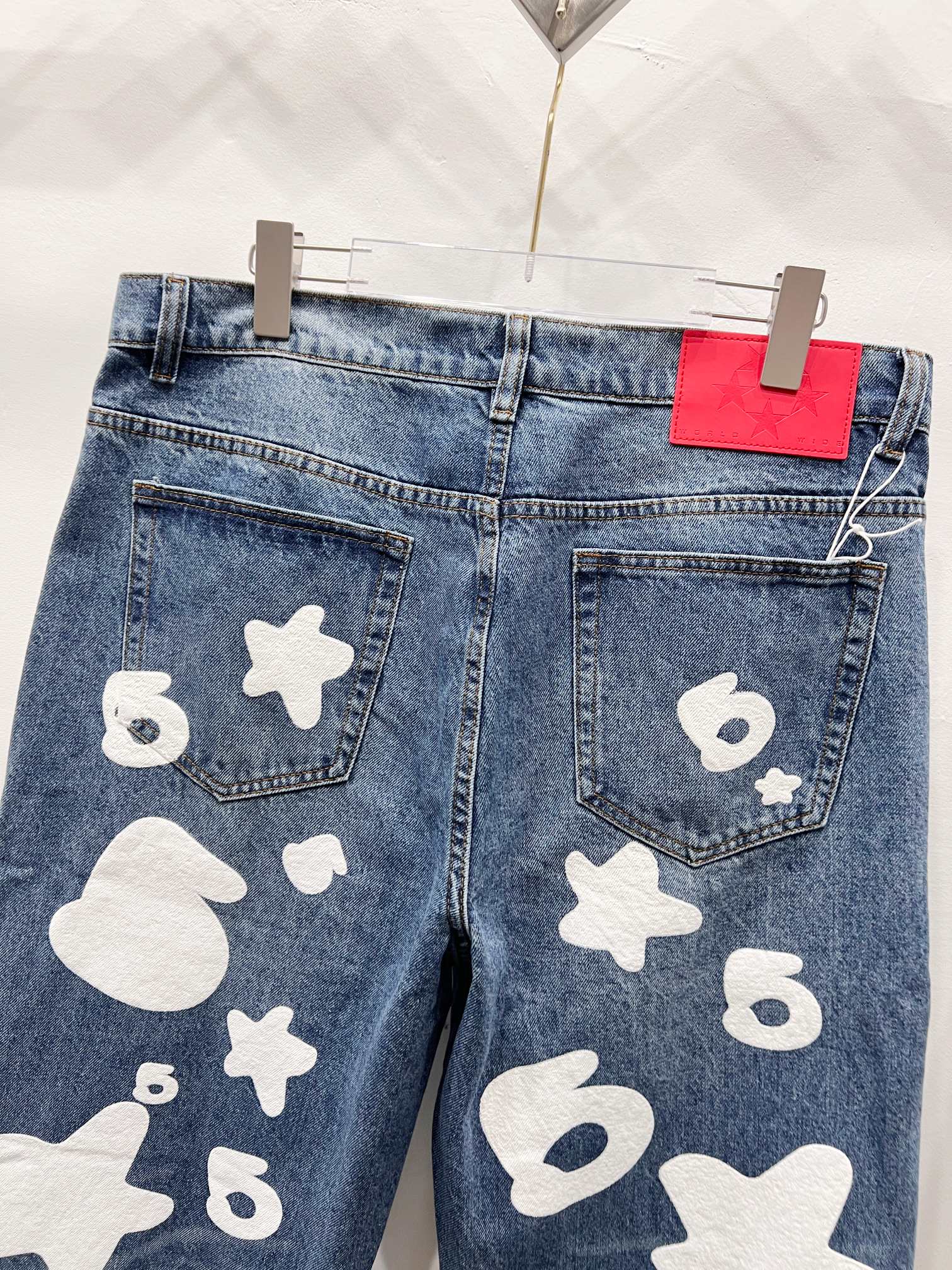 Blue denim pants with white graphic patches, close-up back pockets