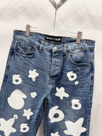 Blue denim pants with white graphic patches, close-up front pockets