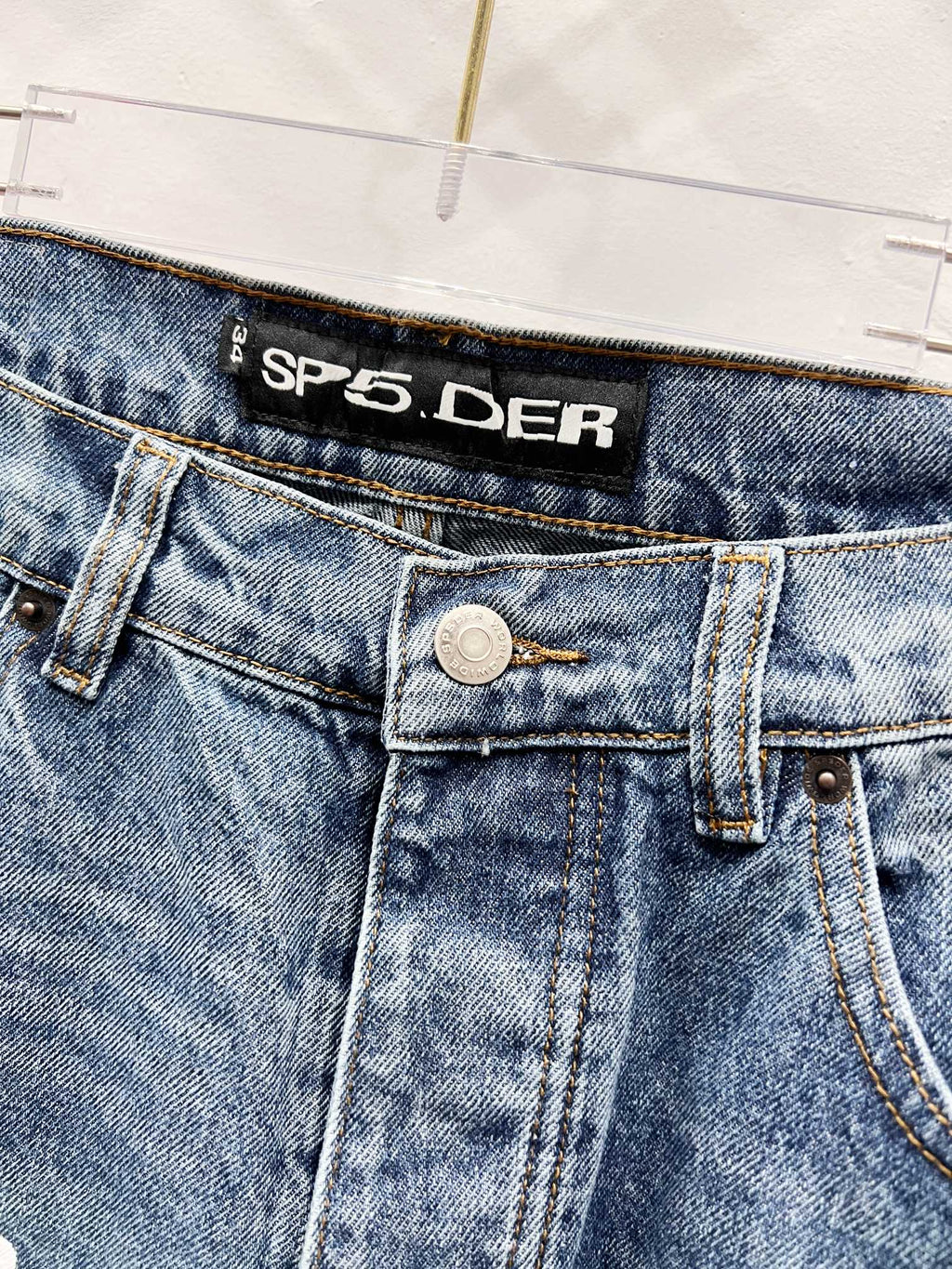 Blue denim pants waistband with logo patch and metal button closure