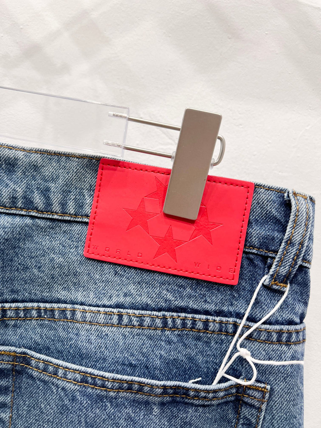 Blue denim pants with red logo patch at waistband and belt loop