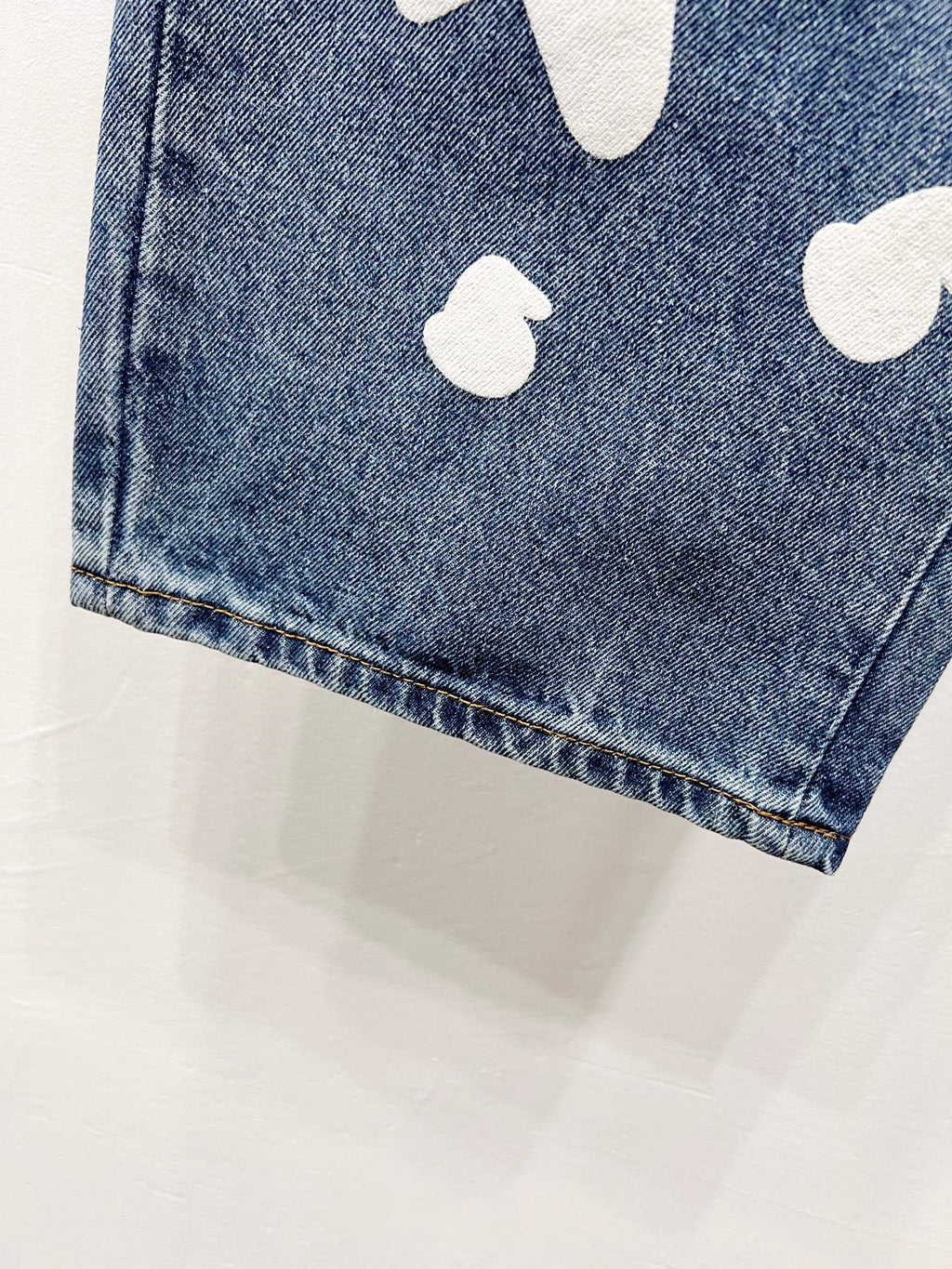 Blue denim pant leg with white graphic patch near hem