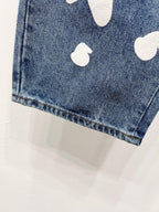 Blue denim pant leg with white graphic patch near hem
